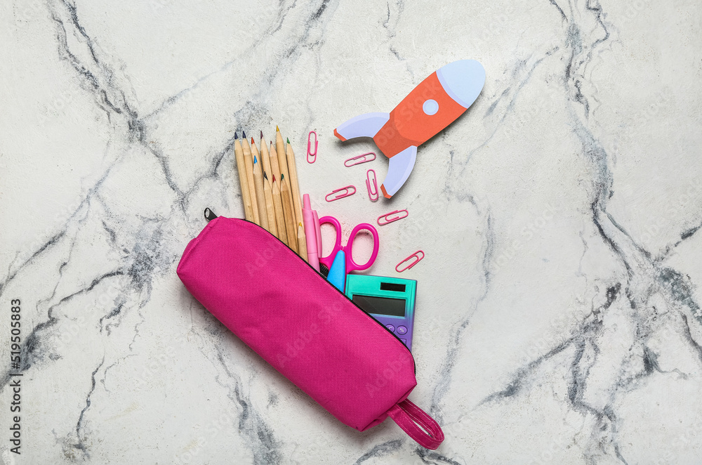 Pencil case with school stationery and paper rocket on light background