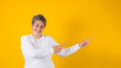 © Marcos - hispanic matured woman pointing to copy space on yellow background in Mexico Latin America