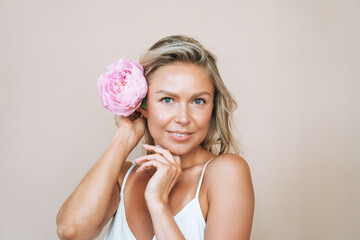 Wall Mural - Beauty portrait of blonde hair smiling young woman with pink peony in hand isolated on white background