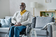 © AnnaStills - Portrait of African mature man with disability sitting in wheelchair in living room and laughing