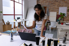 Image Of Biracial Female Artist Using Computer In Studio
