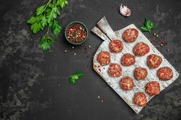 Wall Mural - raw meatballs on wooden board, minced pork meat with spices on a dark background. banner, menu, recipe place for text, top view