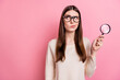 Portrait of attractive suspicious girl using loupe copy space ad isolated over pink pastel color background