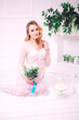 © capable97 - Young attractive bride with blond hair with wedding makeup and hairstyle in a white lace peignoir with bride's bouquet in a bright interior