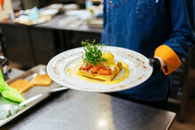 Chef Holding Plate Of Toast With Poached Egg, Salmon And Mustard Sauce