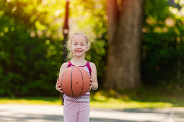 Little girl with basketball on court on summer season