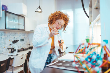 Wall Mural - Beautiful Female Scientist Wearing Protective Goggles Mixing Chemicals in a Test Tube in a Lab. Young Professional Microbiologist Working in Modern Laboratory with Technological Equipment.