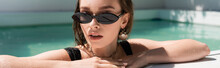 Portrait Of Young And Stylish Woman In Black Sunglasses Resting In Swimming Pool, Banner.