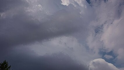 Wall Mural - Low angle shot of fluffy white clouds passing blue sky at daytime. Cumulus cloud cloudscape in timelapse. 
