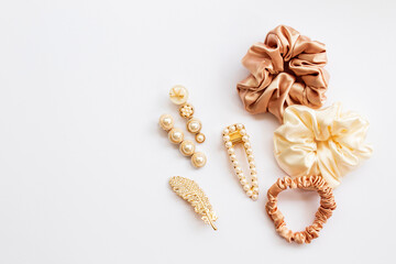 Collection of trendy silk elastic band scrunchies and pearl hair clips on white background. Diy accessories and hairstyles concept, luxury color