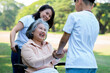 © Prot - Happy senior Asian grandmother uses wheelchair with her daughter and grandchild in park, Grandson came to visit elderly grandmother and hold hand. Concept of happy family, good relationship together