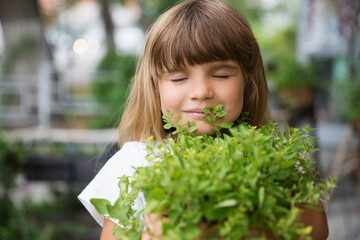 child girl holding pot with mixed green fresh aromatic herbs in garden near the house. enjoy the little things. favorite family hobby. Eco-friendly. 