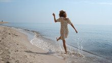 Cheerful Girl Running Ocean Waves Back View. Playful Woman Walking Wet Sand.
