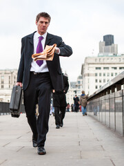 Wall Mural - Late for Work. A smart young business man hurriedly checking the time while crossing London Bridge on his way to the office; from a series of images.