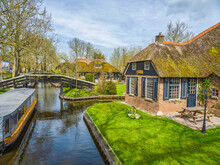 Canal Side Thatched Roof Houses, Bridges And Boat In The Fairy Tale Village Of Giethoorn, Netherlands