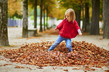 Adorable Preschooler Girl Walking In Tuileries Garden In Paris, On A Fall Day