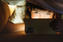 Girl Under A Blanket Using A Mobile Phone