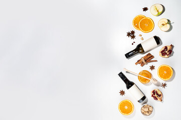 Wall Mural - Different mulled wine ingredients set on white background, flat lay with wine bottle, cinnamon, apple, orange, anise star, simple autumn food drink cooking background