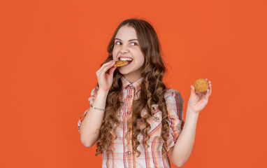 hungry teen girl with oatmeal cookies on orange background