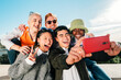 © Jose Calsina - Group of multi-ethnic young friends taking a picture together with a smartphone.