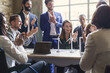 © Lomb - Group of multiethnic coworkers applauding the success of a sustainability project about renewable energy and green power - teamwork clapping hands sitting around the table of the meeting room