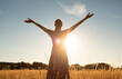 © kieferpix - Young woman in a meadow feeing free, happy in nature with arms up facing beautiful golden sunset