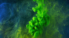 A Beautiful Mixture Of Acrylic Inks In Dark Blue Glittering Water. Stock Footage. Close Up Of Green Ink Stream Forming Amazing Cloud While Mixing With Water.