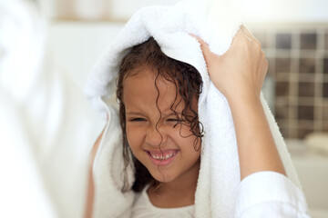 Wall Mural - Haircare routine, cleaning and hair being washed by a mother for her happy, carefree and smiling daughter at home. Loving, caring and kind parent helping her child get dressed, get dry or get clean