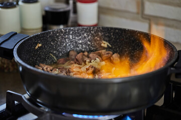 Sticker - Beef meat fried with onions in frying pan, flambe on gas stove