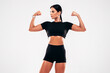 © halayalex - Fitness confident woman in black sports clothing. Sexy young beautiful model with perfect body. Female isolated in studio. Stretching out before training. Posing on grey background. Shows her muscles