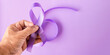 International Overdose Awareness Day. World Cancer Day. Hand holds purple ribbon on the purple background