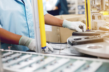 A female worker is working to control an automatic machine for an electronic circuit board product part.