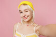 © ViDi Studio - Close up young blond lesbian woman she wear knitted top yellow hat do selfie shot pov on mobile cell phone wink isolated on plain pastel light pink background People lgbtq lifestyle fashion concept.