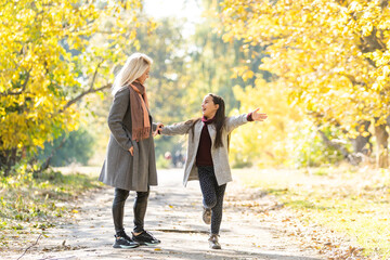 Wall Mural - Little girl and her mother enjoy sunny weather in the autumn park