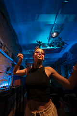 Wall Mural - Beautiful female DJ dancing to techno in a small club