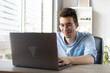 © Djordje - Happy young man in glasses with laptop computer working at home office. technology, remote job and lifestyle concept .