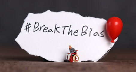 Wall Mural - Torn paper with the word ‘BreakTheBias' written on it. Break the bias campaign with a miniature man in a wheelchair.
