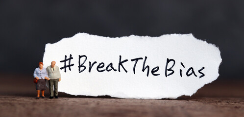 Wall Mural - Torn paper with the word ‘BreakTheBias' written on it. Break the bias campaign with miniature old people.
