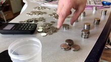 Poor Person Stacks Many Of Small Coins In Column.