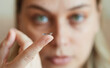 © evafesenuk - Focus on finger, young woman holding a contact lens in front of her face