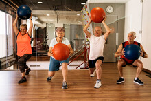 Group Of Athletic Senior Friends Exercising With Medicine Balls In Gym