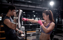 Young Woman Fitness Wearing Hand Bandage Ready To Boxing Throw A Punch With Trainer Couple Lover Holding Pads For Boxing Session ,they Exercise For Strong Make Muscle And Good Healthy Lifestyle.