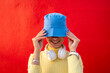 © VISTA by Westend61 - Smiling woman with headphones covering face with blue bucket hat