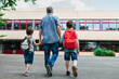 © Elena Medoks - Back to school. View from the back of a happy dad escorts his sons schoolchildren to school. Parental care for children