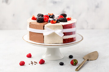 Wall Mural - Selection of various cake pieces - cheesecake, chocolate cake, red velvet on cake stand on white stone background with berries. Overhead view, flat lay