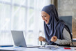 © crizzystudio - Happy Muslim businesswoman wearing hijab Muslim female office employee looking at laptop screen, celebrating success