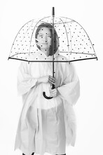 Studio Shot Of Beautiful Asian Woman With Long Black Hairs Wearing Raincoat And Hiding Under Transparent With Black Dots Umbrella With Copy Space In White Background. Black And White Image