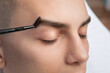 © Dimid - The makeup artist plucks the eyebrows of a handsome young man. Professional make-up and face care.