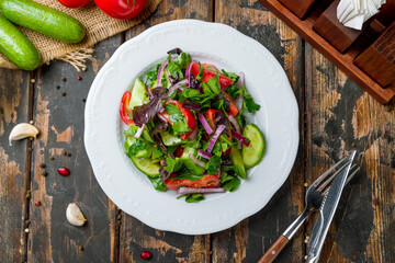 Wall Mural - Vegetable salad with tomatoes and cucumbers with red onion top view on old wooden table