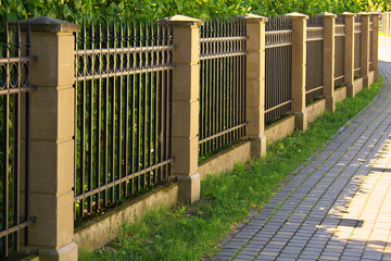 Green and metal fence separating the street and private property. Maintains privacy and security.